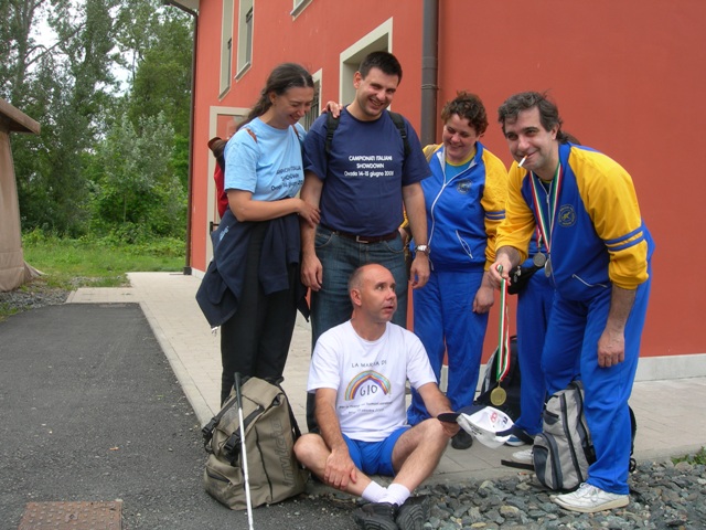 Un capannello di curiosi, guarda un povero cieco che tenendo un cappello in grembo mendica... Arriva Domenico, che mosso a compassione, riempie il cappello di Maurizio con la Medaglia!